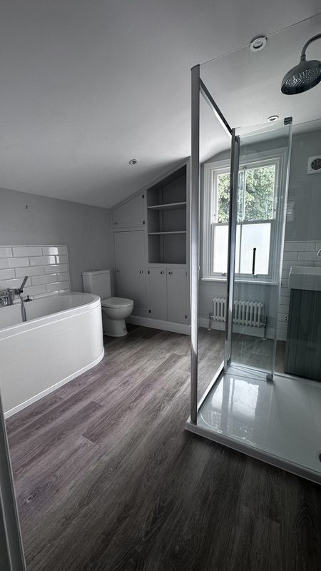 The old main bathroom, a white bath and grey floor.