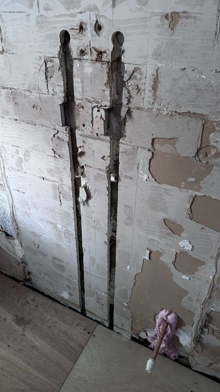 A bathroom wall stripped back for the new pipework.