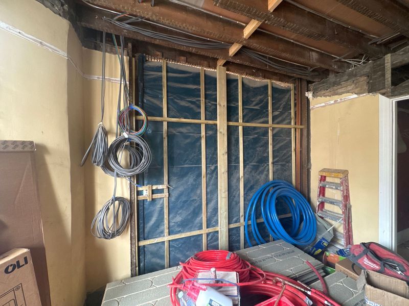 A front room stripped to its studs, the wall lined and battened