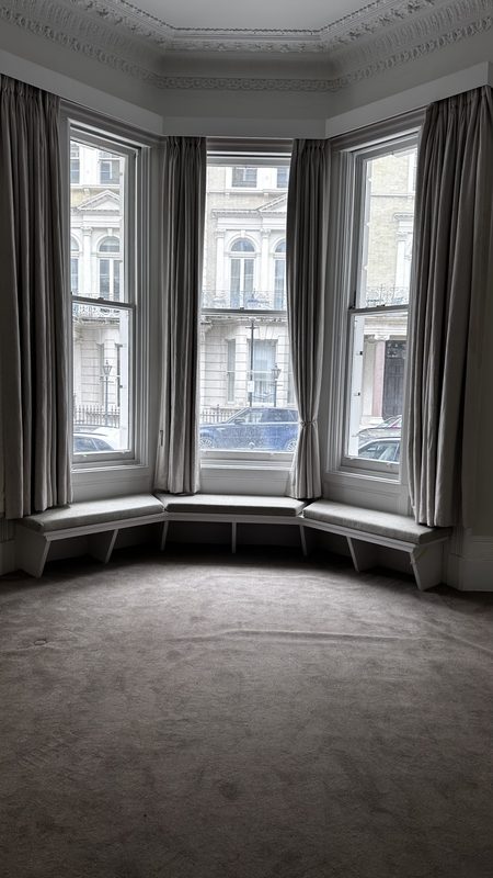The bay window of the drawing room before the work, grey carpet and long curtains.