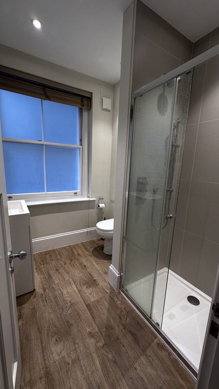 The old shower room, a glass enclosure and timber effect floor.