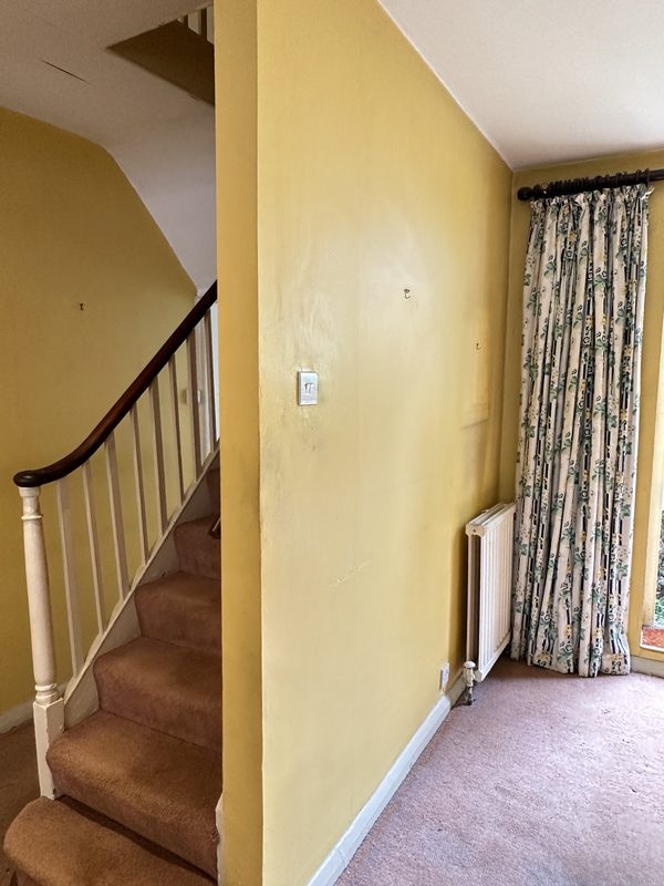 The old staircase and hall, with brown carpet and yellow walls.