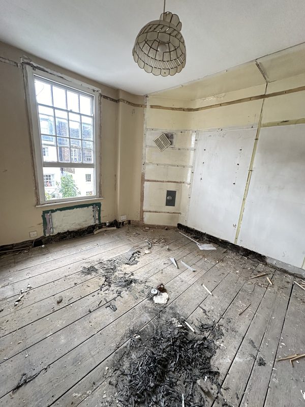 A front room stripped back, bare boards and old lining on the walls.