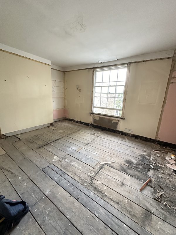 A bedroom emptied of its fittings, with bare floorboards.