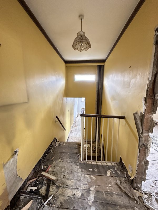 The landing during the strip out, old banisters and torn floor.