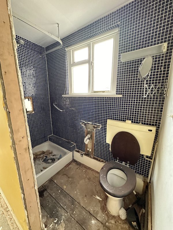 The old bathroom, blue tiles and a dated WC.