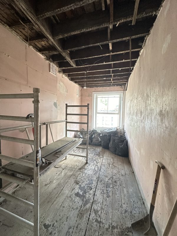 A room under strip out, scaffold tower and bare walls.