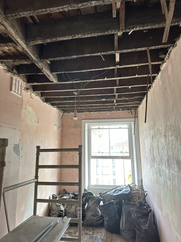 A stripped room, the ceiling down to its joists.