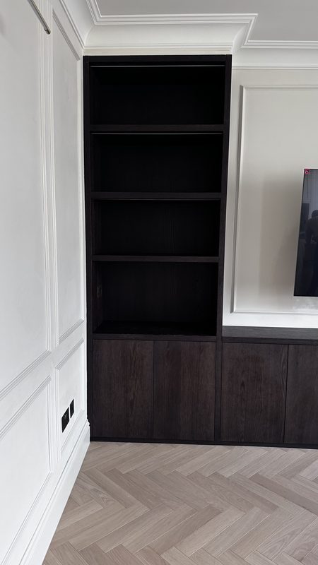 The finished living room shelving, dark joinery beside panelled walls.