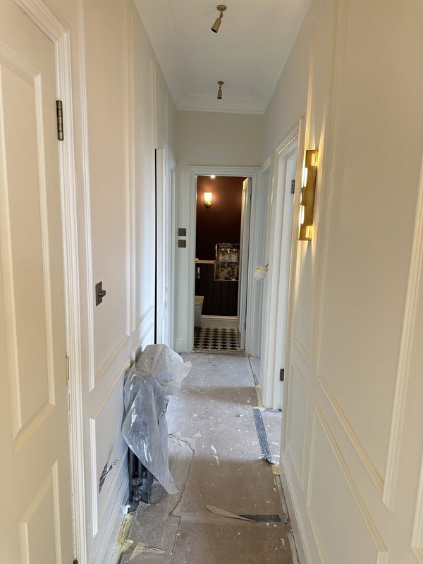 The panelled corridor with brass wall lights.