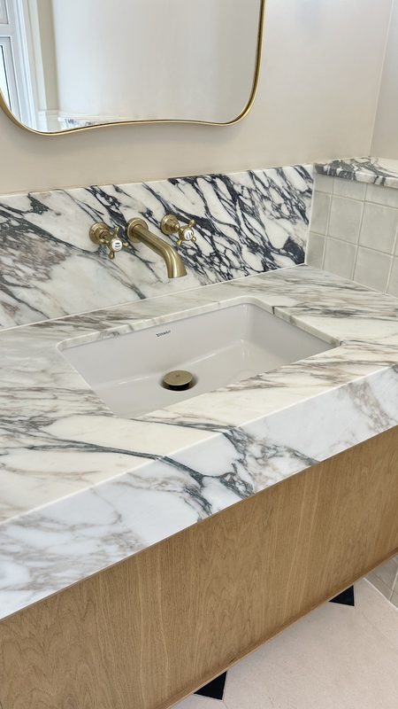 A Calacatta Viola marble vanity with brass taps.