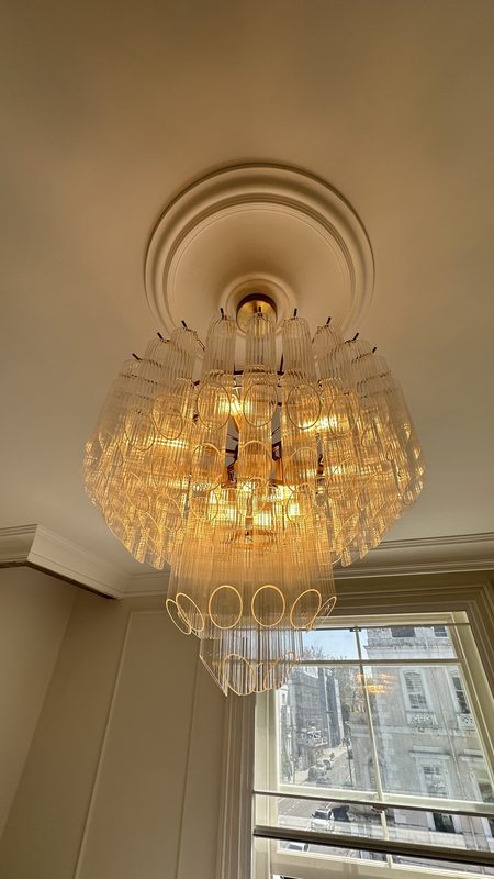 A crystal chandelier under a ceiling rose.