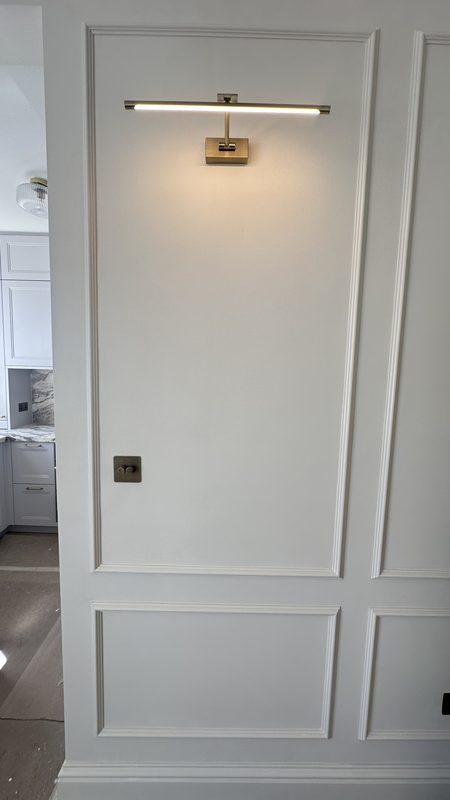 A panelled door with a brass picture light above.