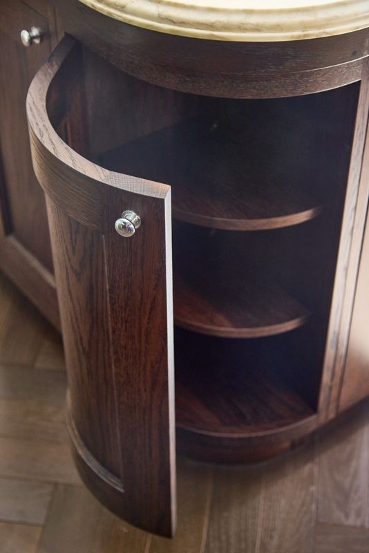 Curved oak door opened on a round cupboard with fitted shelves.