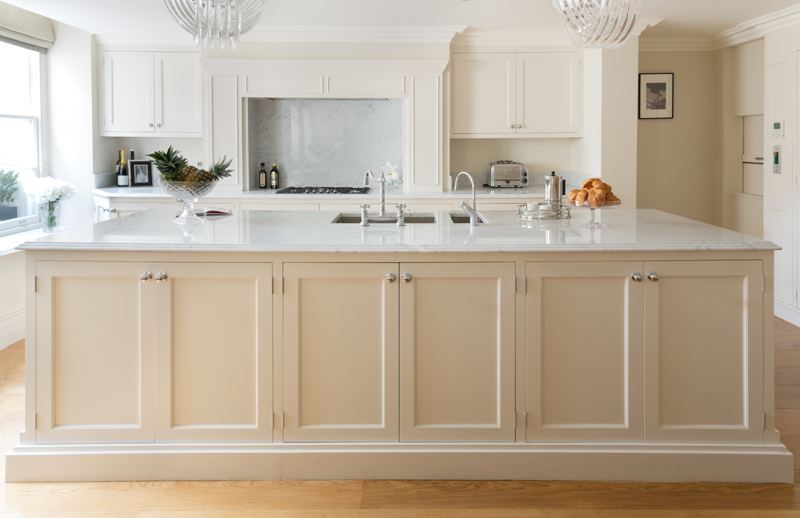 Cream painted island with a marble top and fielded panel doors.