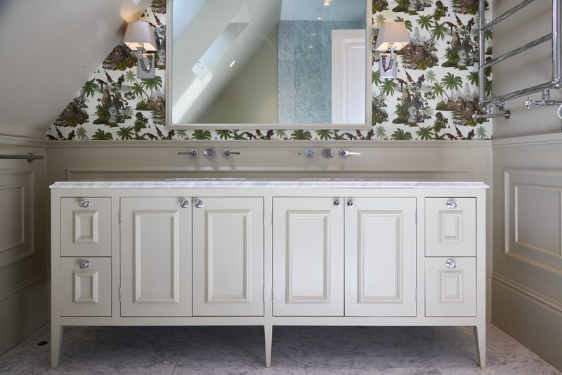 Painted vanity with twin basins below a wide framed mirror.