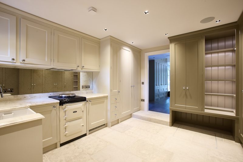 Cream painted kitchen and boot room with a stone floor.