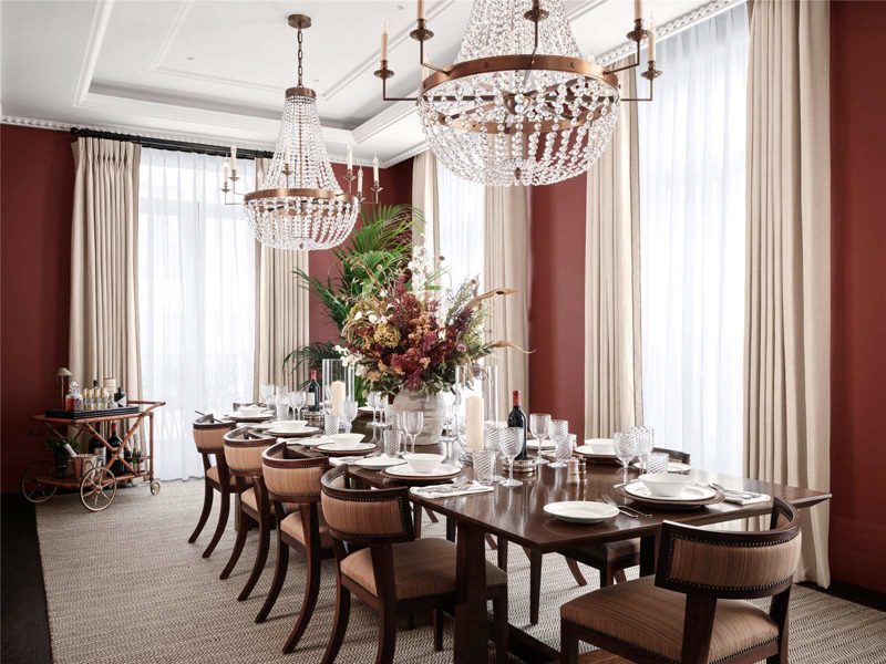 Dining room with red walls and two glass chandeliers.