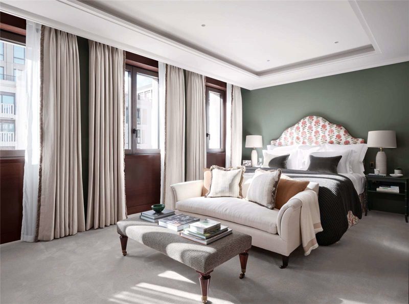 Bedroom with tall windows and a patterned upholstered headboard.