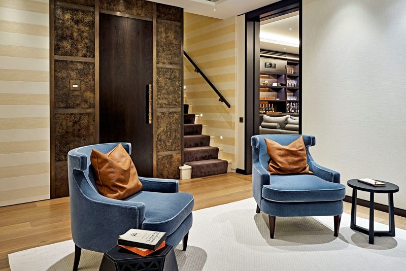 Entrance lobby with blue velvet chairs and a bronze door.