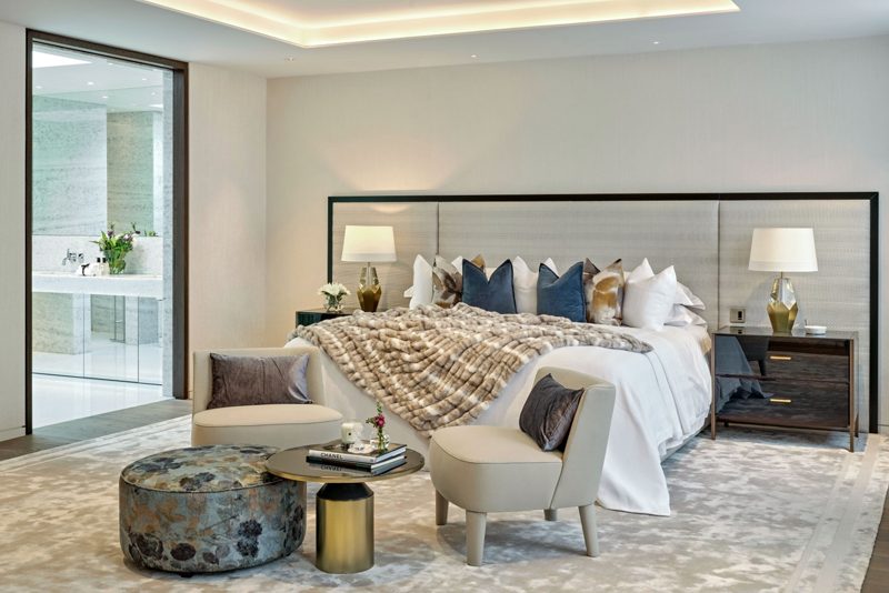 Bedroom with a wide headboard and a stone bathroom beyond.