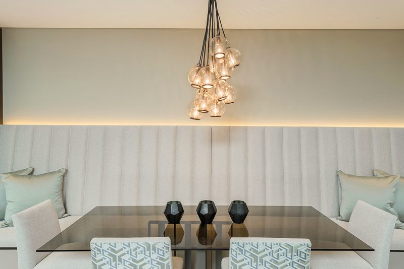 Dining banquette below a cluster of glass pendant lights.