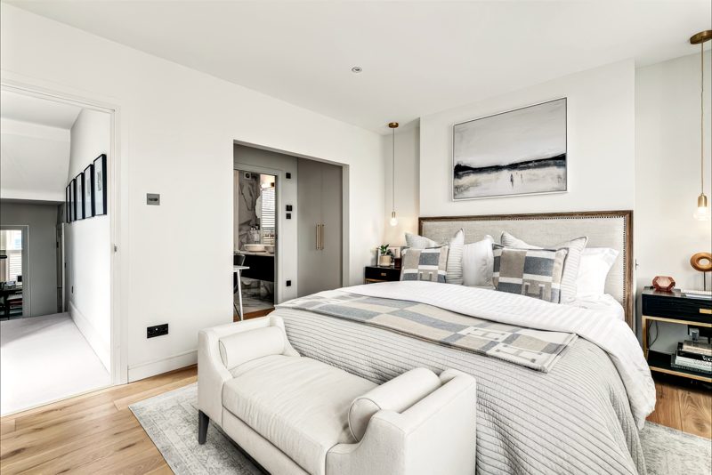 Main bedroom with a padded headboard, open to the dressing room.