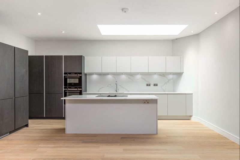 Kitchen with pale units and a long stone topped island.