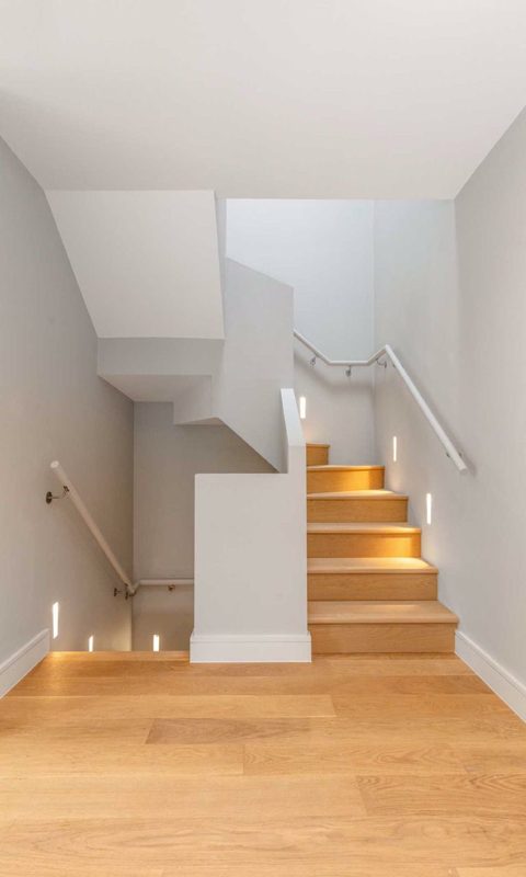 Staircase with pale treads and lit niches in the wall.