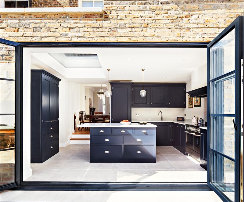 Glazed rear extension opening onto a navy kitchen with a central island.