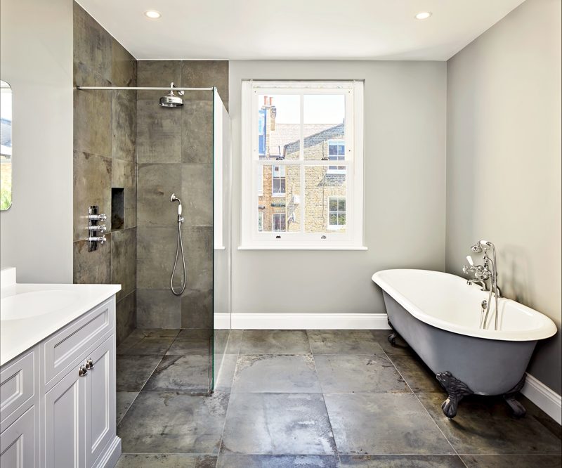 Bathroom with a roll-top bath, a stone floor and a walk-in shower.