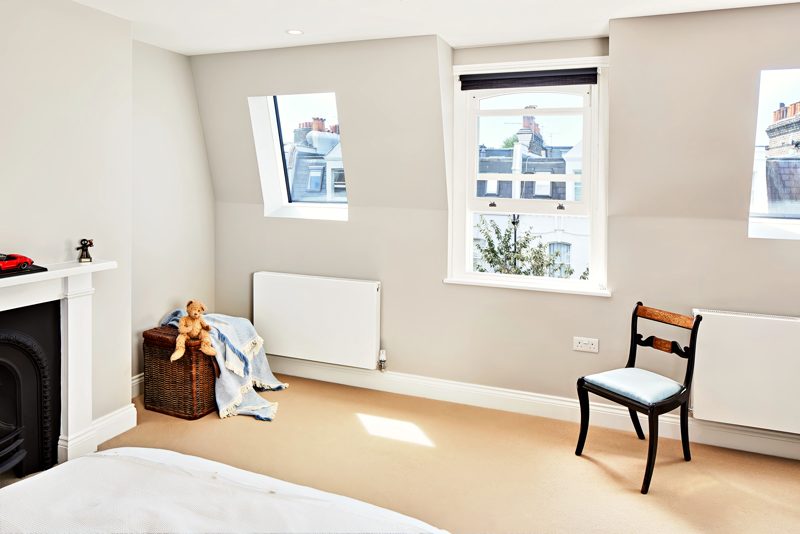 Bedroom under the eaves, with a fireplace and three windows.