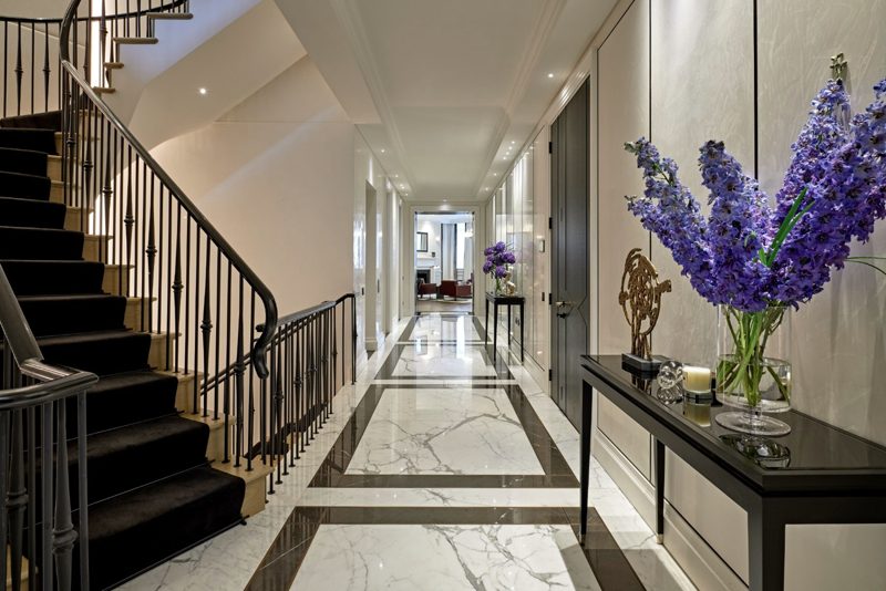 Entrance hall with a marble floor and a curving staircase.