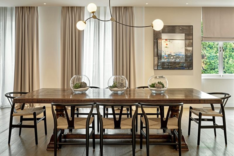 Dining room with a long table under a glass chandelier.