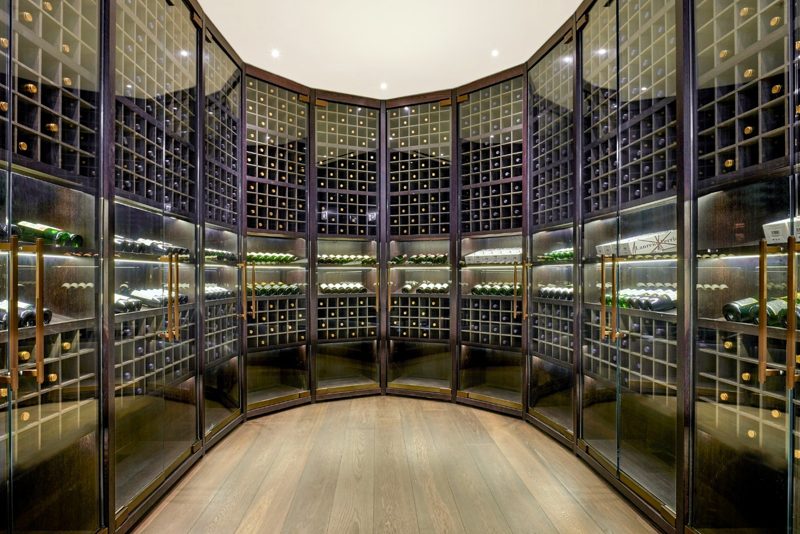 Wine room with glazed doors and racked bottles, warmly lit.