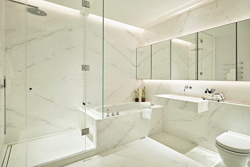 Bathroom in white marble with a large mirror and chrome fittings.