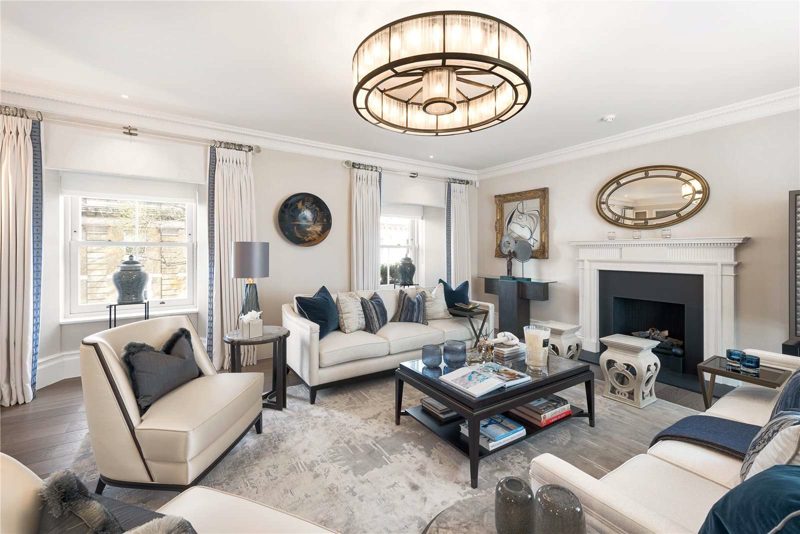 Living room with a fireplace, tall windows and a chandelier.