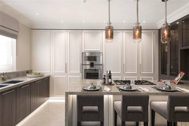 Kitchen with pale units, stone worktops and a small island.