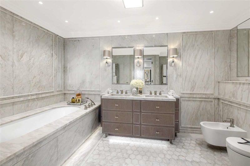 Bathroom in pale marble with a large mirror and basin.