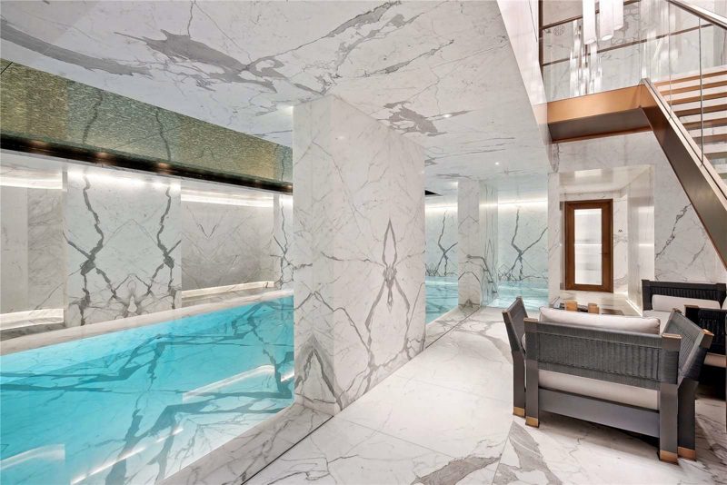 Swimming pool lined in marble with a lit ceiling above.