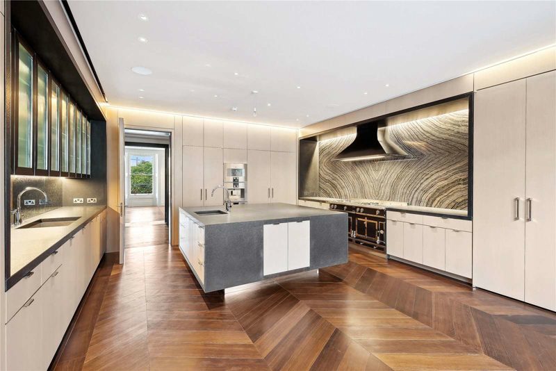 Kitchen with chevron parquet and a veined stone splashback.