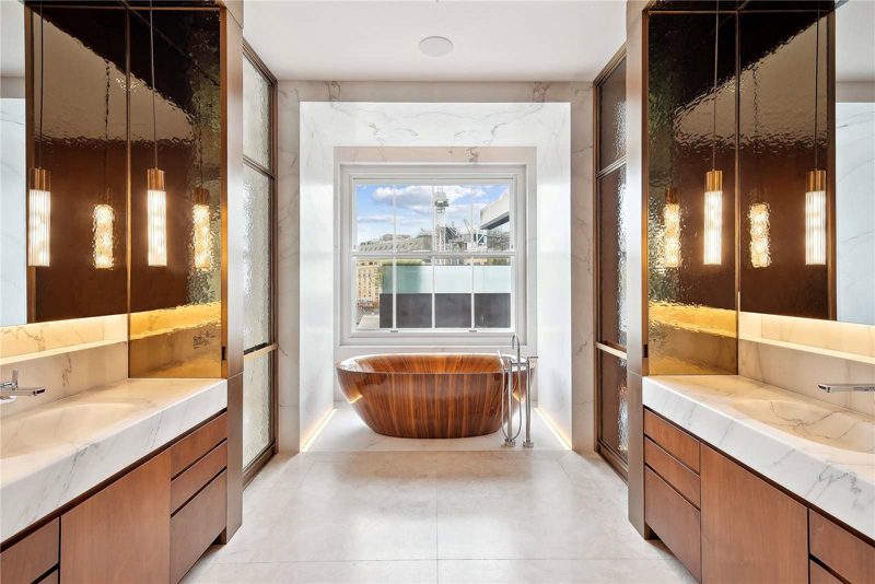 Bathroom with a timber freestanding bath between bronze mirrors.