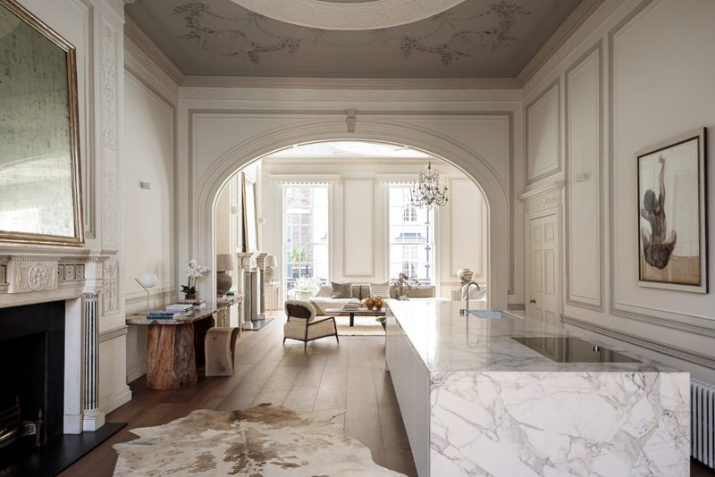 Kitchen with a marble waterfall island set inside a panelled period room.