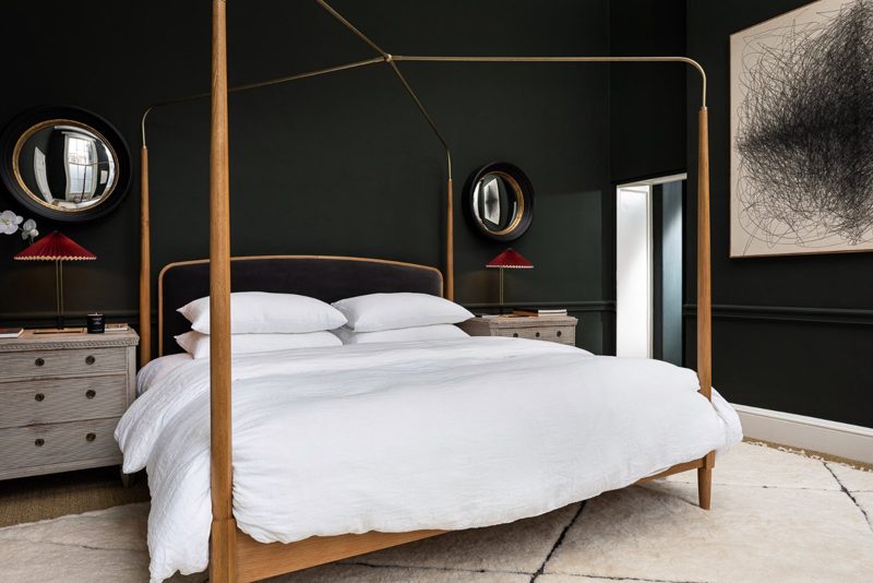 Bedroom with dark walls and a four poster bed in pale timber.