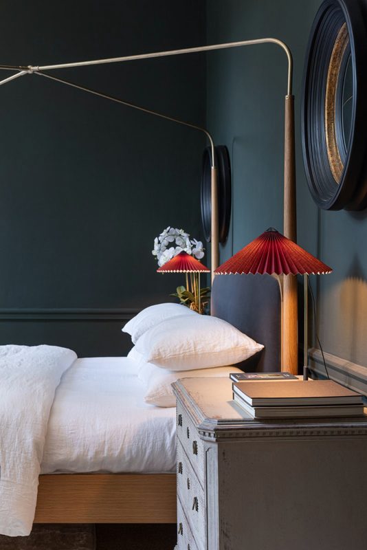 Bedside detail with a red lamp against a dark wall.