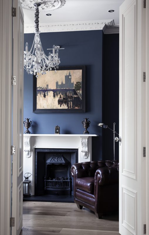 Sitting room with navy walls, a fireplace and a chandelier.