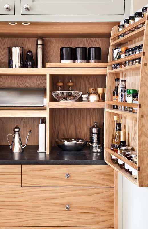 Oak larder opened to show shelves and a fitted spice rack.