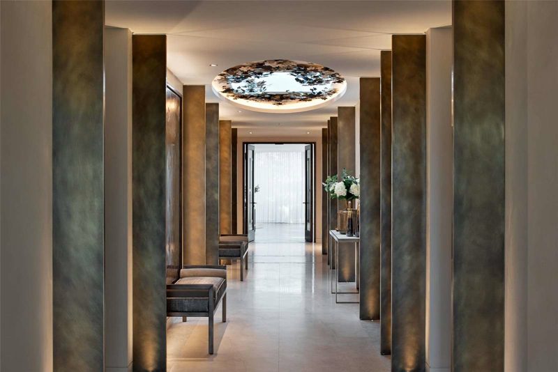 Corridor between bronze columns below a lit circular ceiling panel.