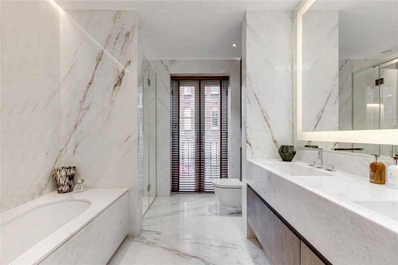 Bathroom lined in veined marble with a wall mounted basin.