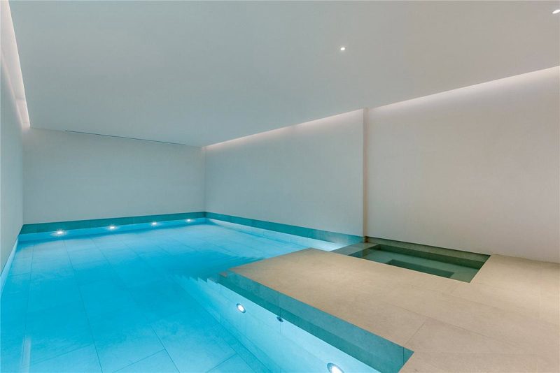 Indoor swimming pool in the basement, lit along both walls.